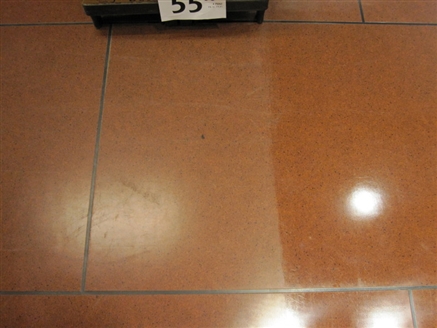 The scratches in the tile are still present but less visible in the polish treated area. The floor is completely clean.
